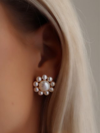 Pearl stud earring close-up worn in ear, showing detail and scale