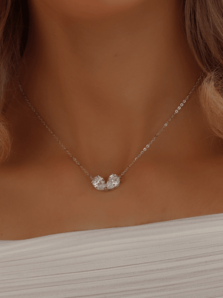 Adore necklace worn by model in a white dress, featuring pear-shaped CZ stones on a white gold plated chain, styled for elegant and romantic occasions