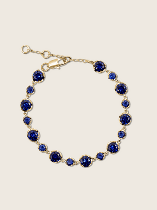 Clarissa Bracelet in 14k gold plating with deep blue cubic zirconia stones in graduated sizes, displayed on neutral background