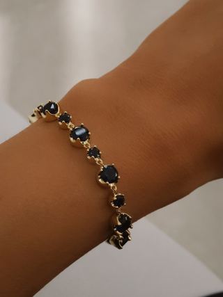 Clarissa Bracelet with 14k gold plating and deep blue cubic zirconia stones shown on wrist close-up