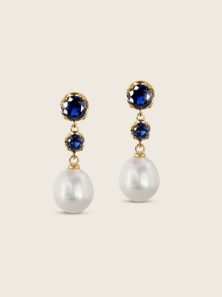 Clarissa Earrings in 14k gold plating with deep blue cubic zirconia and pearl drop, displayed on neutral background