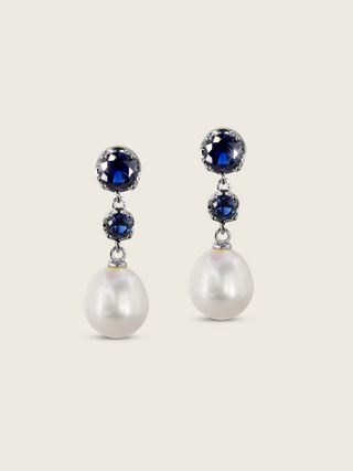 Clarissa earrings in white gold plating with deep blue gemstones and freshwater pearl drops, elegant dangle earrings for formal or evening wear. Displayed on a clear white background