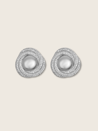 Pearl and CZ swirl earrings on neutral background, white gold plated