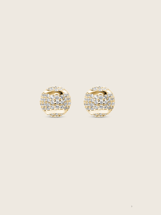 Gold plated sterling silver stud earrings shaped like tennis balls with pavé cubic zirconia stones on neutral background