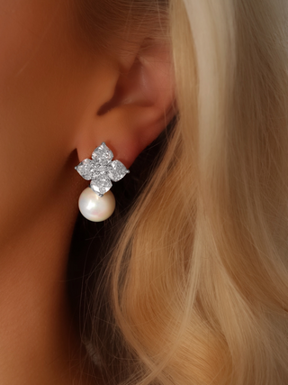Close-up of a model wearing the Crystal Hydrangea Earrings with Shell Pearl, showing the radiant CZ floral top and the elegant shell pearl drop in a white gold-plated sterling silver setting.