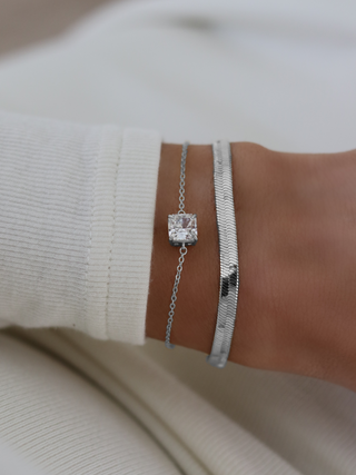Dakota herringbone bracelet in premium White Gold plating styled with the Regina bracelet featuring a solitaire cubic zirconia, worn on model’s wrist