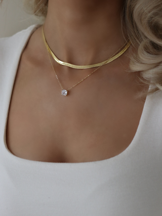 Dakota herringbone necklace in 14k gold plating layered with the Regina solitaire pendant necklace, styled with a white ribbed top