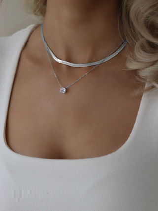 Model wearing Dakota herringbone necklace in premium White Gold plating, layered with the Regina necklace featuring a solitaire cubic zirconia pendant