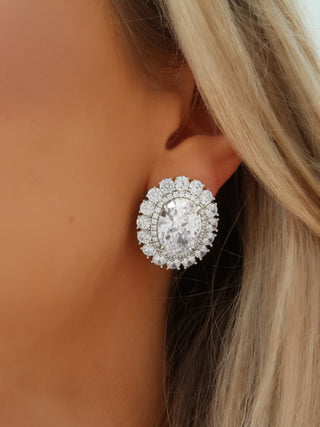 Close-up of model wearing Diana earrings with clear crystal CZ stones in a sparkling oval silhouette with White Gold finish