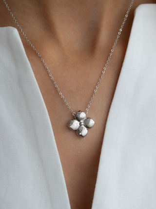 Silver necklace with a floral clover pendant on a model's neckline
