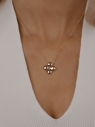 Gold plated Florence necklace worn on model. Shiny hydrangea-shaped pendant on a fine chain, designed for elegant minimalist styling.