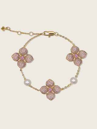 Gold plated hydrangea bracelet with light pink cubic zirconia stones and freshwater pearls on white background