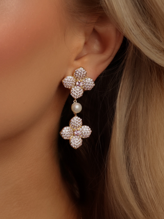 Light pink CZ and freshwater pearl drop earrings in gold, worn on model with soft waves, offering movement and gentle sparkle for elevated looks