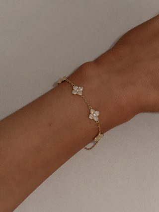 Top view of gold Multi Mini Hydrangea bracelet styled on wrist against a soft neutral background