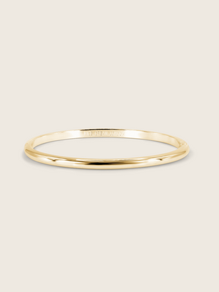 Gold plated slim Christy bangle on white background. Simple and elegant polished bangle, ideal for stacking or wearing alone.