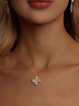 Gold-plated hydrangea necklace with light pink CZ stones worn by model, showcasing floral pendant and fine chain detail