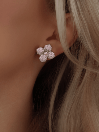 Close-up of light pink Hydrangea stud earring with pavé petals and pink centre stone worn on model’s ear, set in White Gold plating
