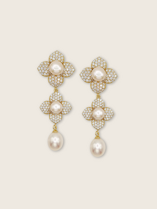 Triple flower drop earrings with freshwater pearls and CZ stones in 14k gold plating on a cream background