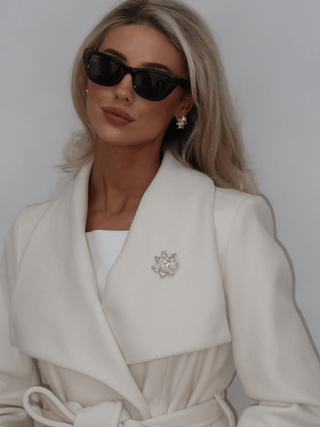 Model wearing Iris Brooch in 14k gold plating with clear marquise cut cubic zirconia stones on coat paired with matching Iris Earrings