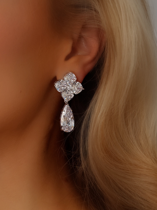 Close-up of a model wearing the Large Crystal Hydrangea Pear Drop Earrings, showcasing the bold pear-shaped CZ drop and the finely cut hydrangea top in a white gold-plated sterling silver setting.