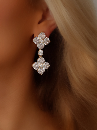 Close-up shot of a model wearing large gold-plated double crystal drop earrings, showcasing the sparkle of the CZ stones and the luxurious design