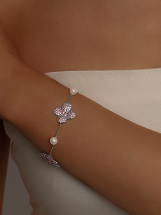 White Gold-plated hydrangea bracelet with light pink stones and freshwater pearls worn by model in ivory satin top