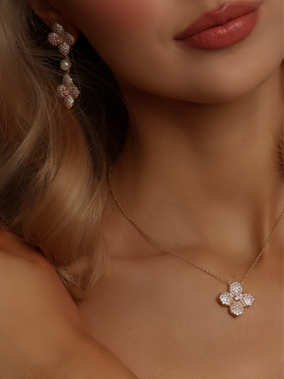 Detail of gold-plated hydrangea pendant necklace and drop earrings with light pink CZ stones and pearl accents