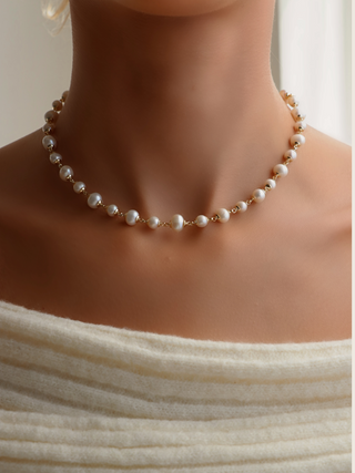 Detailed view of gold-plated Margot necklace with irregular freshwater pearls styled with soft ivory off-shoulder knit