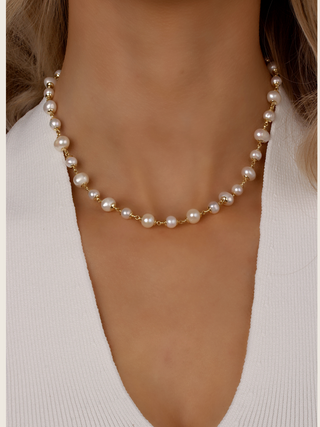 Close-up of gold-plated Margot pearl necklace with natural freshwater pearls worn with white knit top