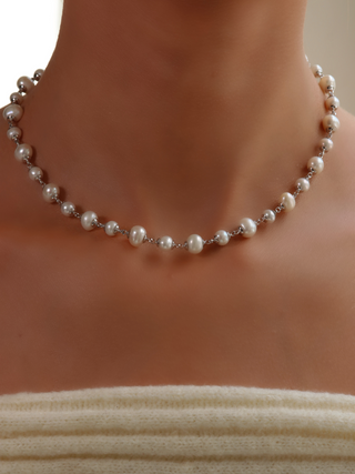 Detailed view of White Gold-plated Margot necklace with irregular freshwater pearls, styled with off-shoulder ivory knit top