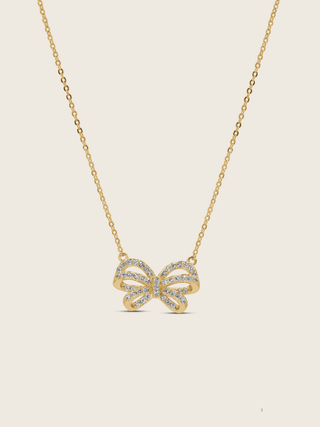 Meredith Bow Necklace in 14k gold plating with crystal pavé bow on fine chain, displayed on neutral background