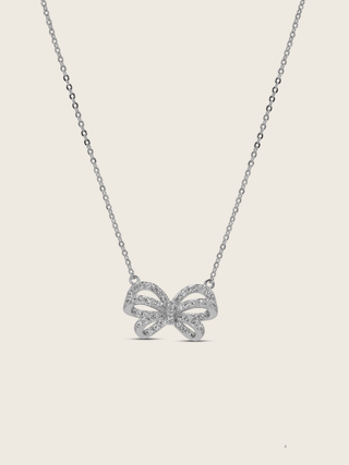 Meredith Bow Necklace in premium White Gold plating with crystal pavé bow on fine chain, displayed on neutral background