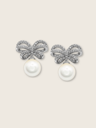 White background product image of white gold bow earrings with shell pearl drop