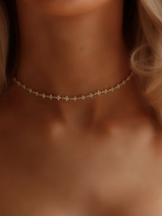 Micro hydrangea pavé necklace in gold, worn on model’s neckline, showcasing the intricate design and sparkling details of the piece.
