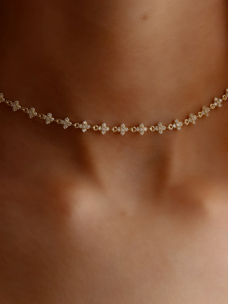 Close-up of micro hydrangea pavé necklace in gold, highlighting the intricate flower petal details on the pendant, worn on model’s neckline.
