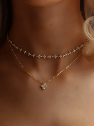 Micro hydrangea pavé necklace in gold stacked with mini hydrangea necklace, worn on model’s neckline, showcasing the layered look and size comparison of the pieces.