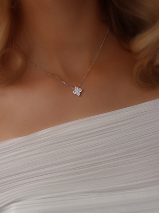 Close-up of a model wearing the Mini Crystal Hydrangea Necklace with a white dress, showcasing the delicate sparkle of the pendant against her neckline.