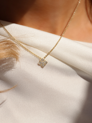Gold plated Mini Hydrangea necklace with pavé flower pendant photographed in natural light on cream fabric, highlighting texture and sparkle