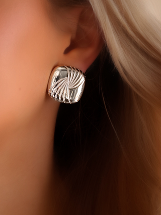 Close-up of the Miranda earrings worn on the model’s ear, showcasing the high-polish sterling silver and white gold plating, with a bold 80s-inspired sculpted curve that adds a powerful statement to any look.