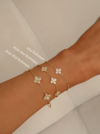 Stacked view of three gold plated Hydrangea bracelets on model’s wrist, including Mini, Multi Mini, and Multi Midi styles