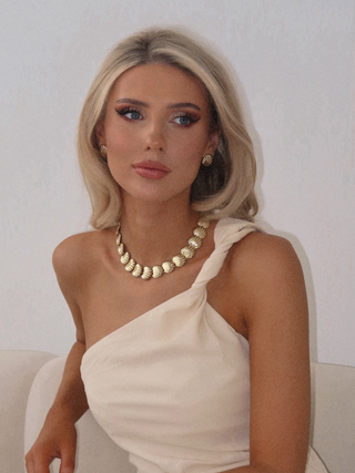 Model wearing Muriel necklace with matching shell earrings in polished 14k gold finish