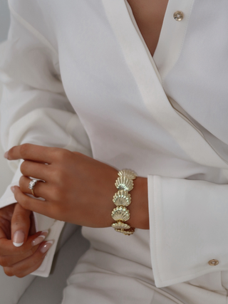 Model wearing the Muriel bracelet with polished gold shell links for a summer inspired look