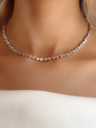 Close-up of the Serena tennis necklace with bezel-set round CZ stones and white gold plating, worn elegantly at the collarbone for a timeless and versatile statement look.