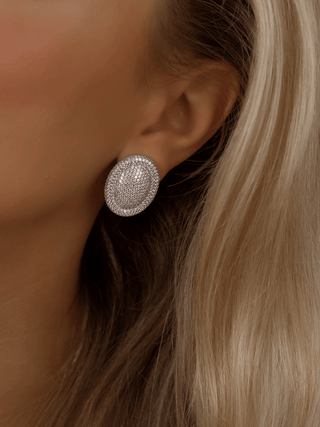 Oval shaped Gigi stud earrings with white gold over sterling silver, set with sparkly CZ stones, worn in model's ear closeup, ideal for brides