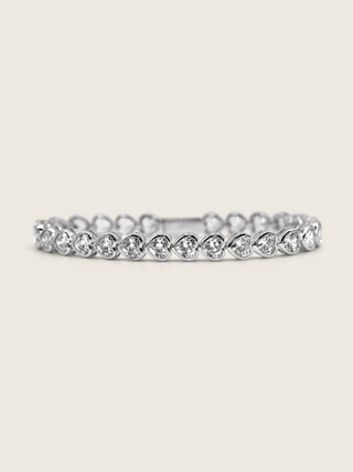 White gold plated heart tennis bracelet with bezel-set heart-cut cubic zirconia stones, a romantic and elegant twist on a classic silhouette