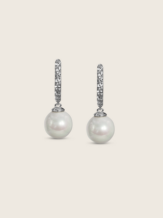 White gold drop earrings with CZ-set hoops and round freshwater pearls, elegant flatlay on cream background