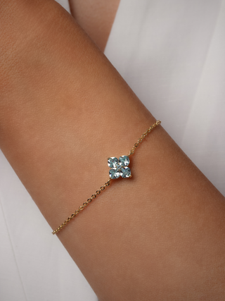 Blue mini crystal hydrangea bracelet with a fine gold plated chain, catching the light on a model's wrist close up