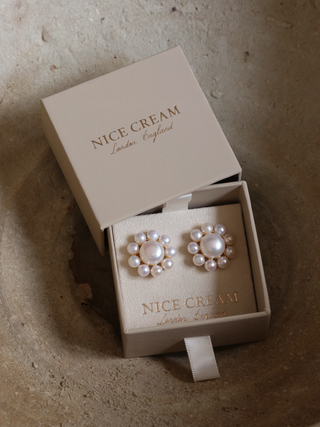 Lustrous white pearl drop earrings displayed in branded gift box, overhead view
