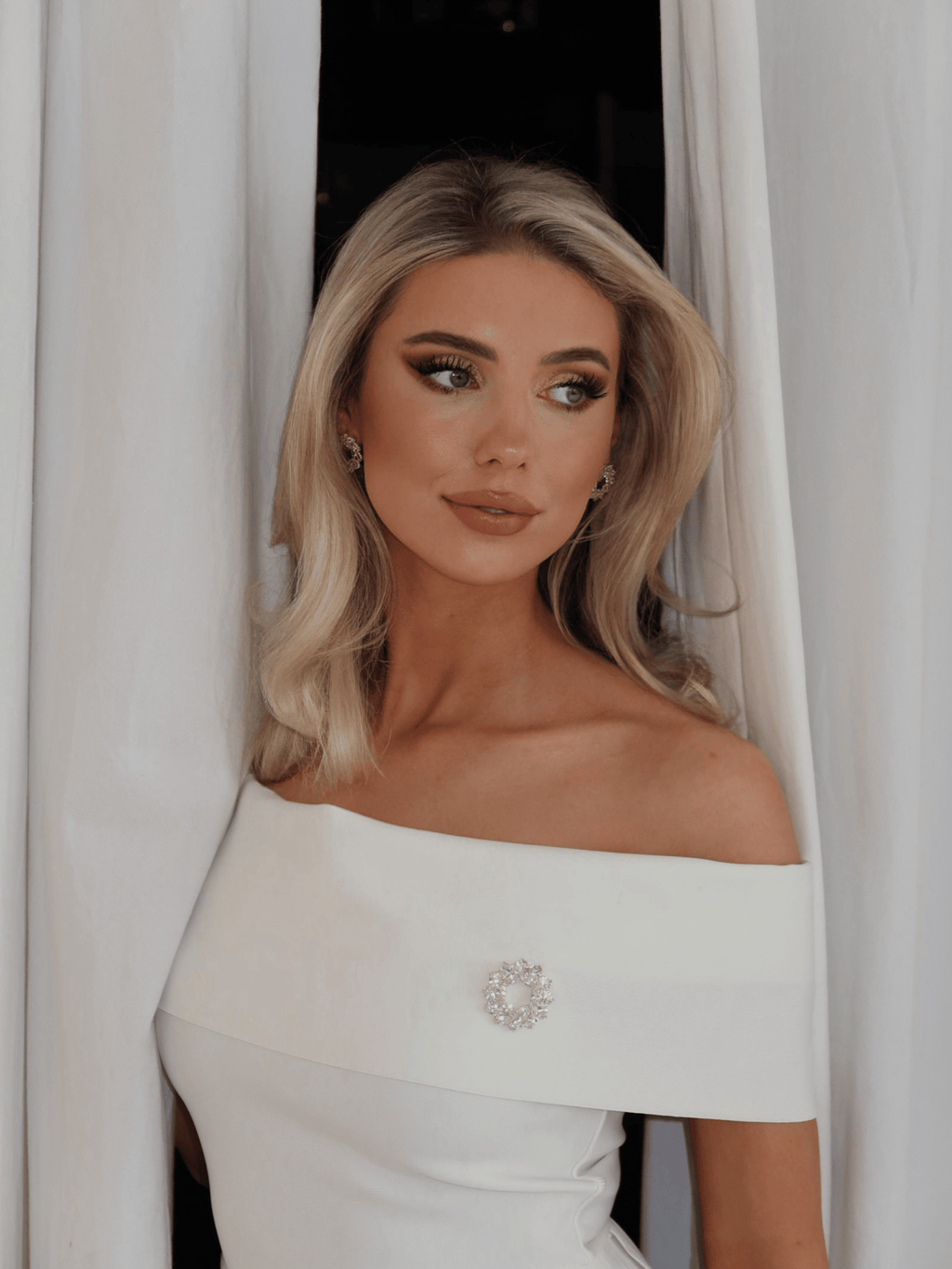 Model wearing Amanda Brooch in 14k gold plating with clear crystal cubic zirconia stones paired with matching Amanda Earrings