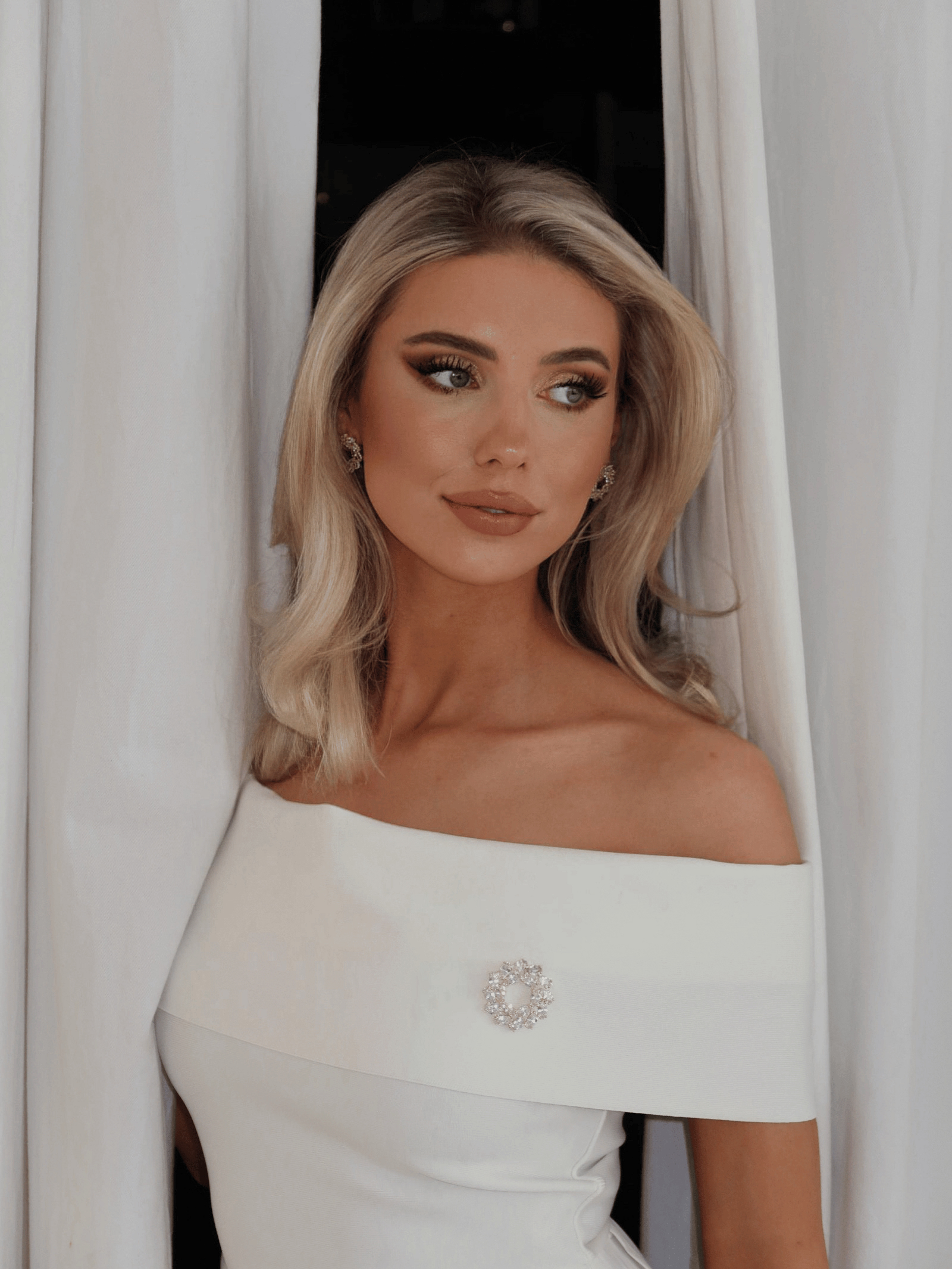 Model wearing Amanda Brooch in 14k gold plating with clear crystal cubic zirconia stones paired with matching Amanda Earrings